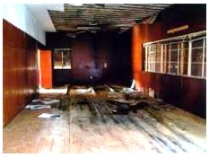 Before: view of damaged floor and plywood paneled walls before construction